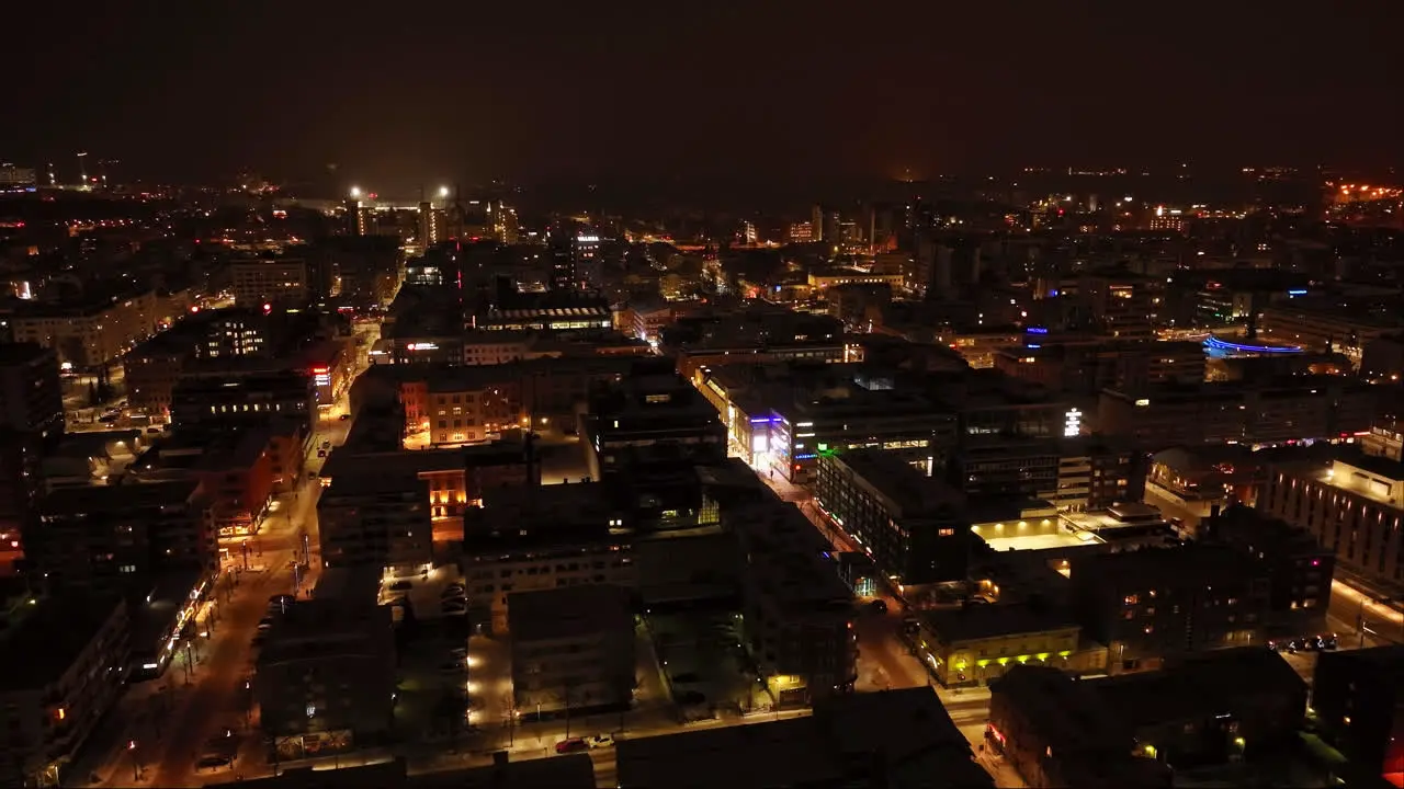 Aerial shot rotating slowly over illuminated streets of Oulu city night in Finland