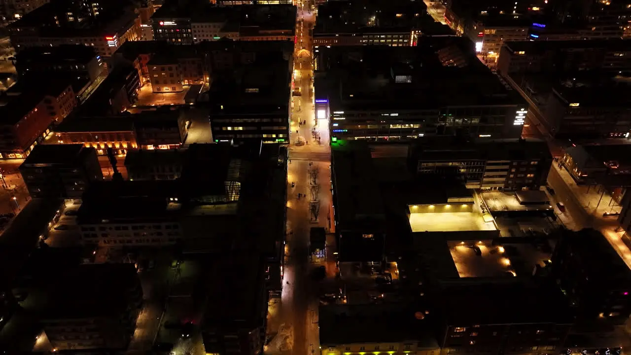 Aerial view tilting over the illuminated streets of downtown Oulu winter night in Finland