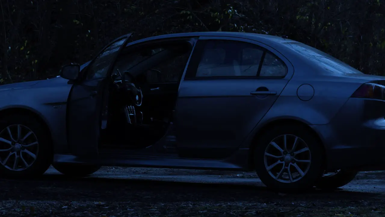 Empty saloon car flashing hazard warning lights abandoned at night on remote road