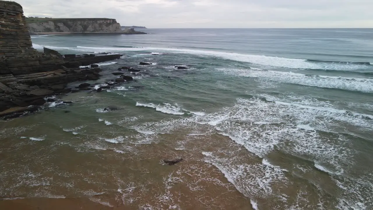 Aerial over ocean cliff waves rolling in on Cantabrian sea shoreline