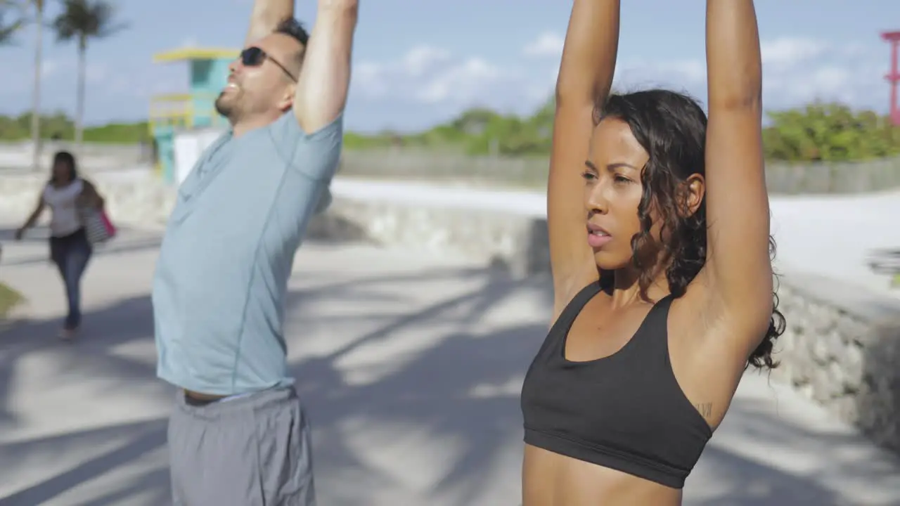 Sporty couple stretching in sunlight