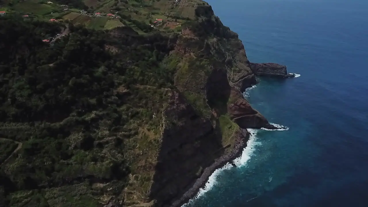 Enjoy stunning drone footage of waves crashing against a majestic mountain in Madeira