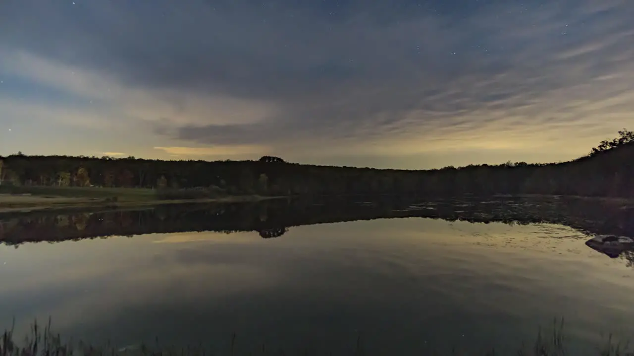 Time Lapse of Stars and Clouds Over a Pond With Reflections