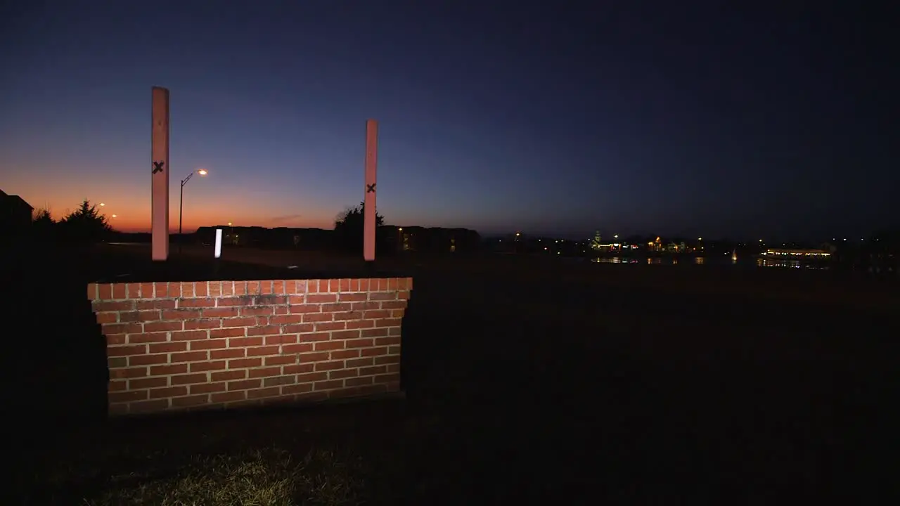 Blank lit up sign at night near sunset next to road on brick platform