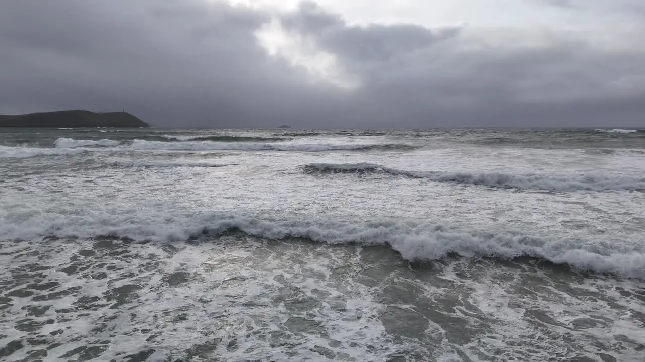 Low drone over waves in sea stormy sky in background