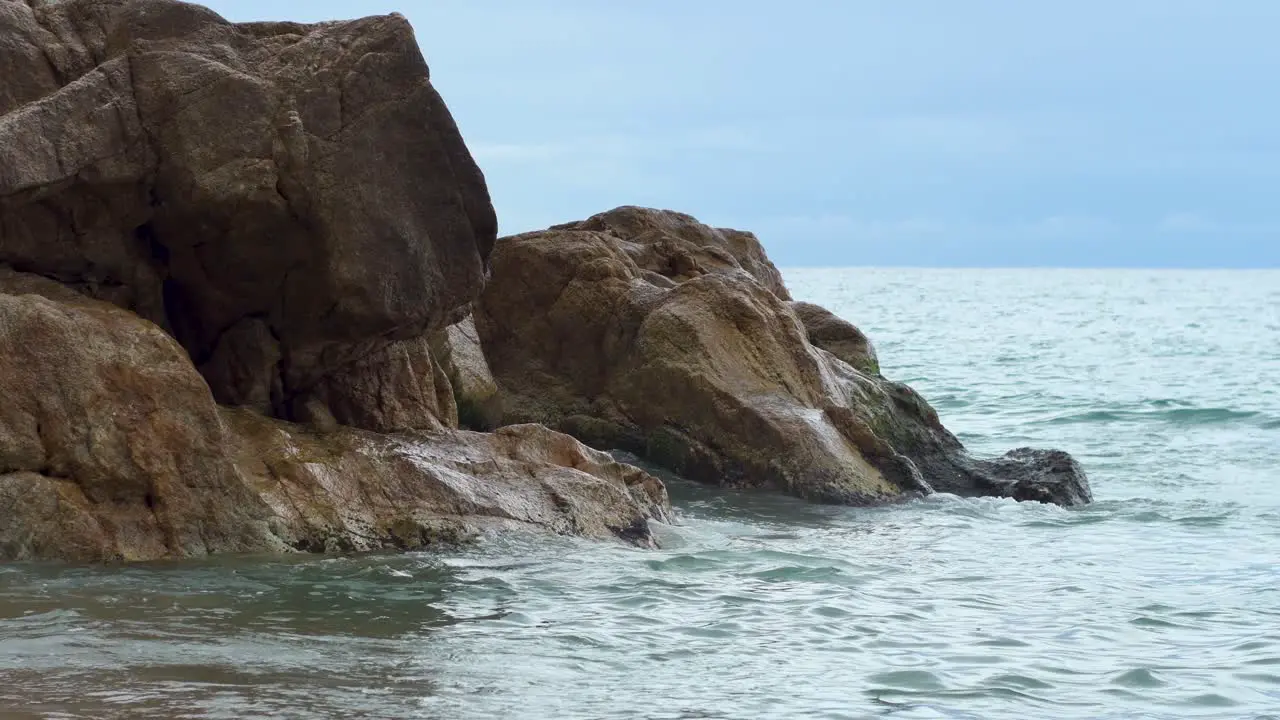 Waves crashing gently on the rock on the shore of the beach on a cloudy day