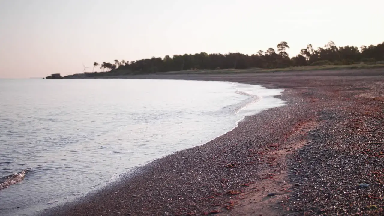 A calm seashore scene with small waves and small rocks in the foreground