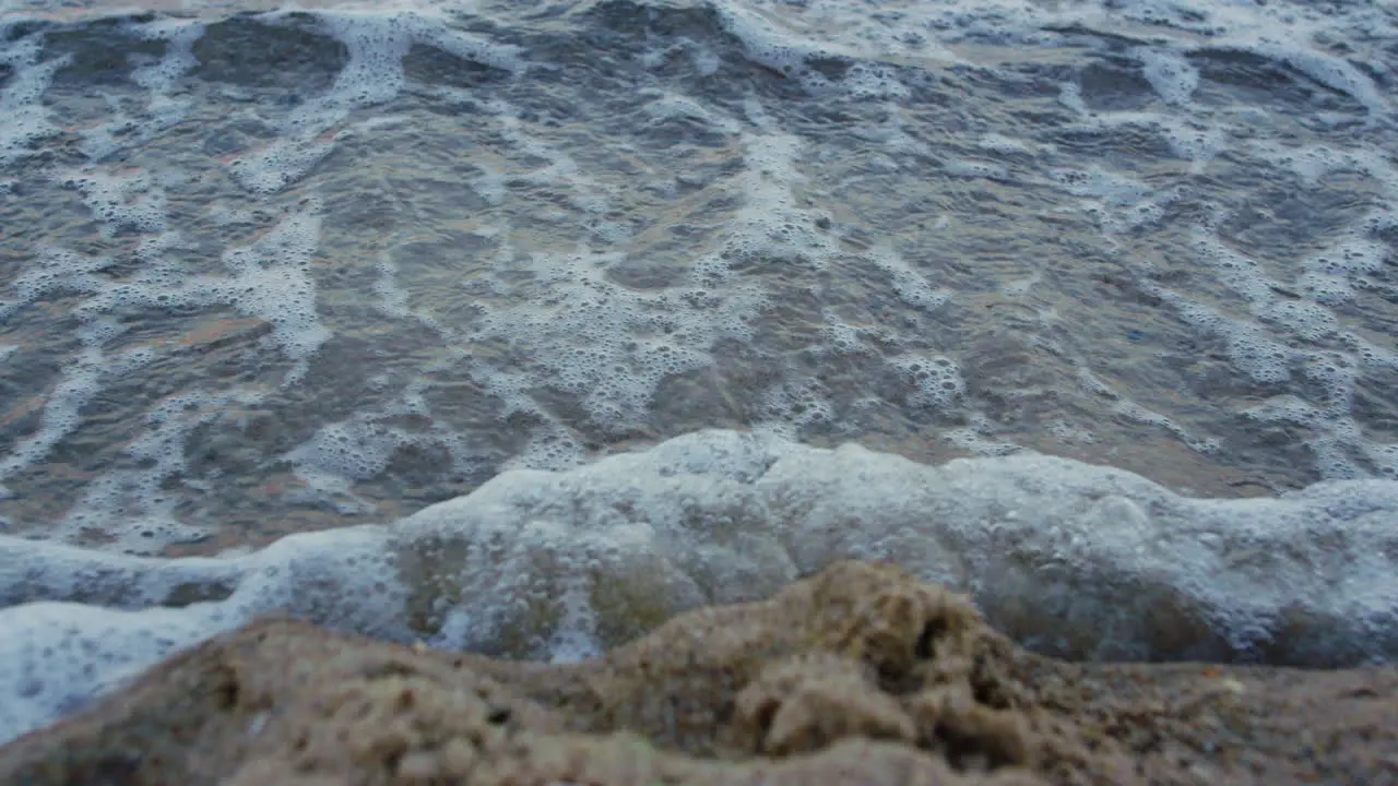 Closeup blue sea waves water washing foot trace on sand beach Nature background