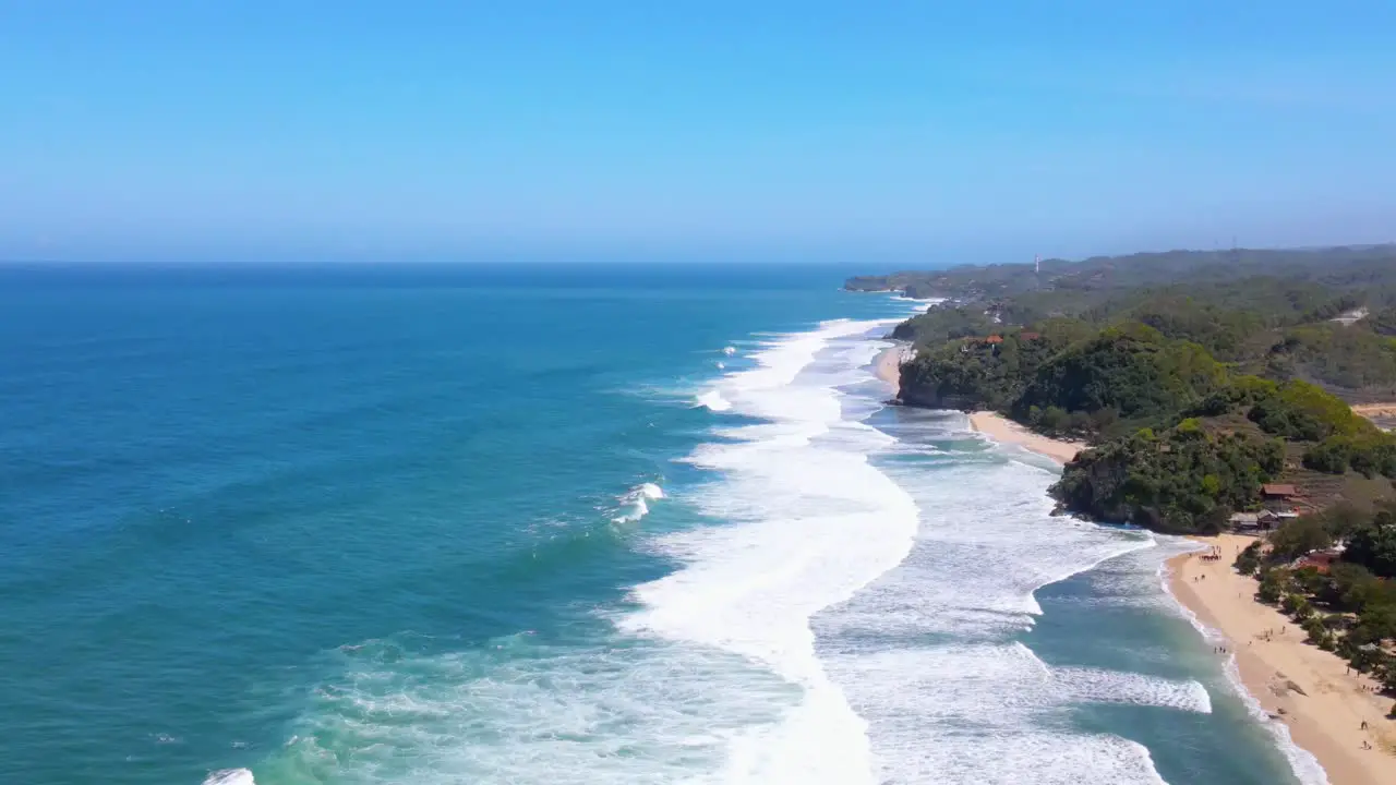 Foamy waves hitting coastline of Indonesia aerial drone view