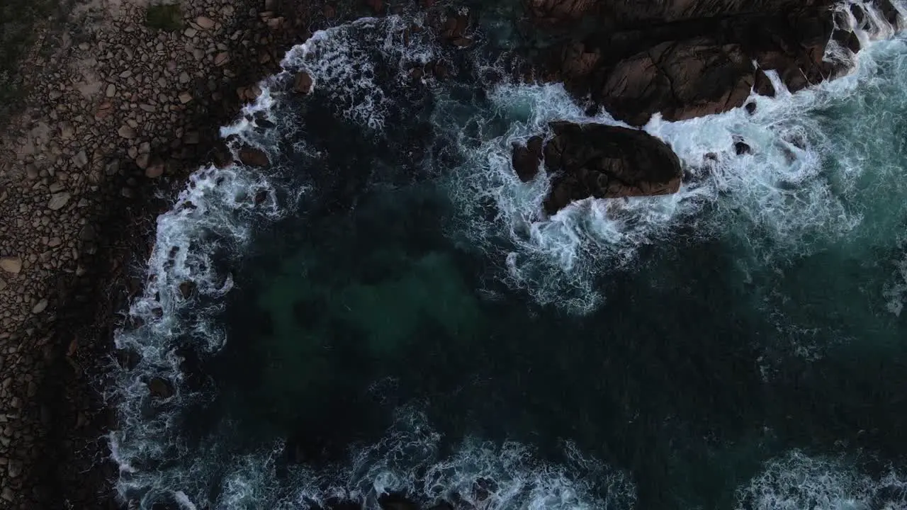 Slow rise and spin over ocean with waves crashing over rocks on the coast