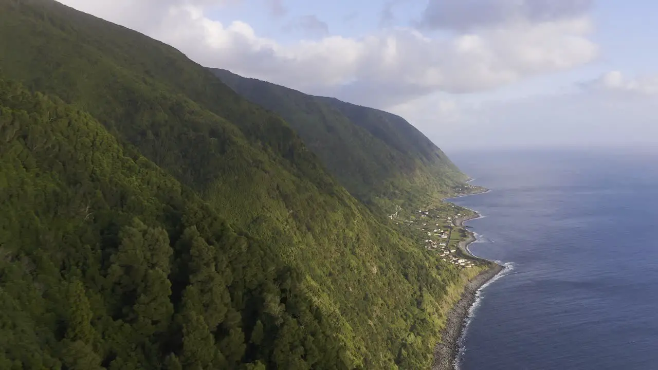 lush green dramatic cliffs over the Atlantic ocean with a rural village São Jorge island the Azores Portugal