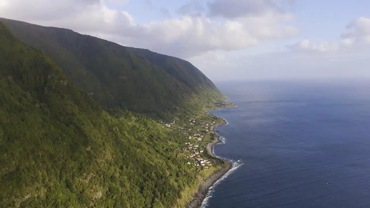 lush green dramatic cliffs over the Atlantic ocean with a rural coastal village São Jorge island the Azores Portugal