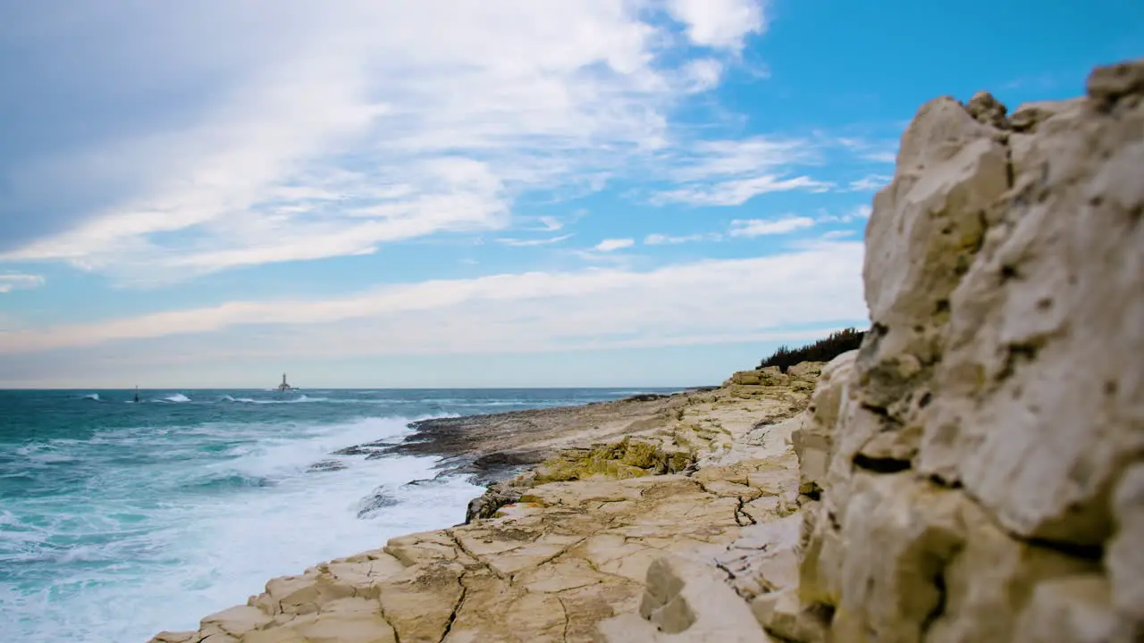 Sea waves creating crest and breaking on rocky coast creating foam and mist focus pull