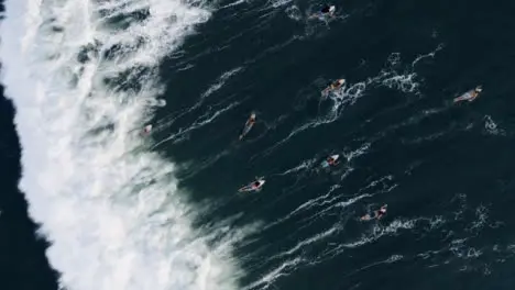 Drone Shot Looking Down On Group of Surfers Attempting Swim Against Waves