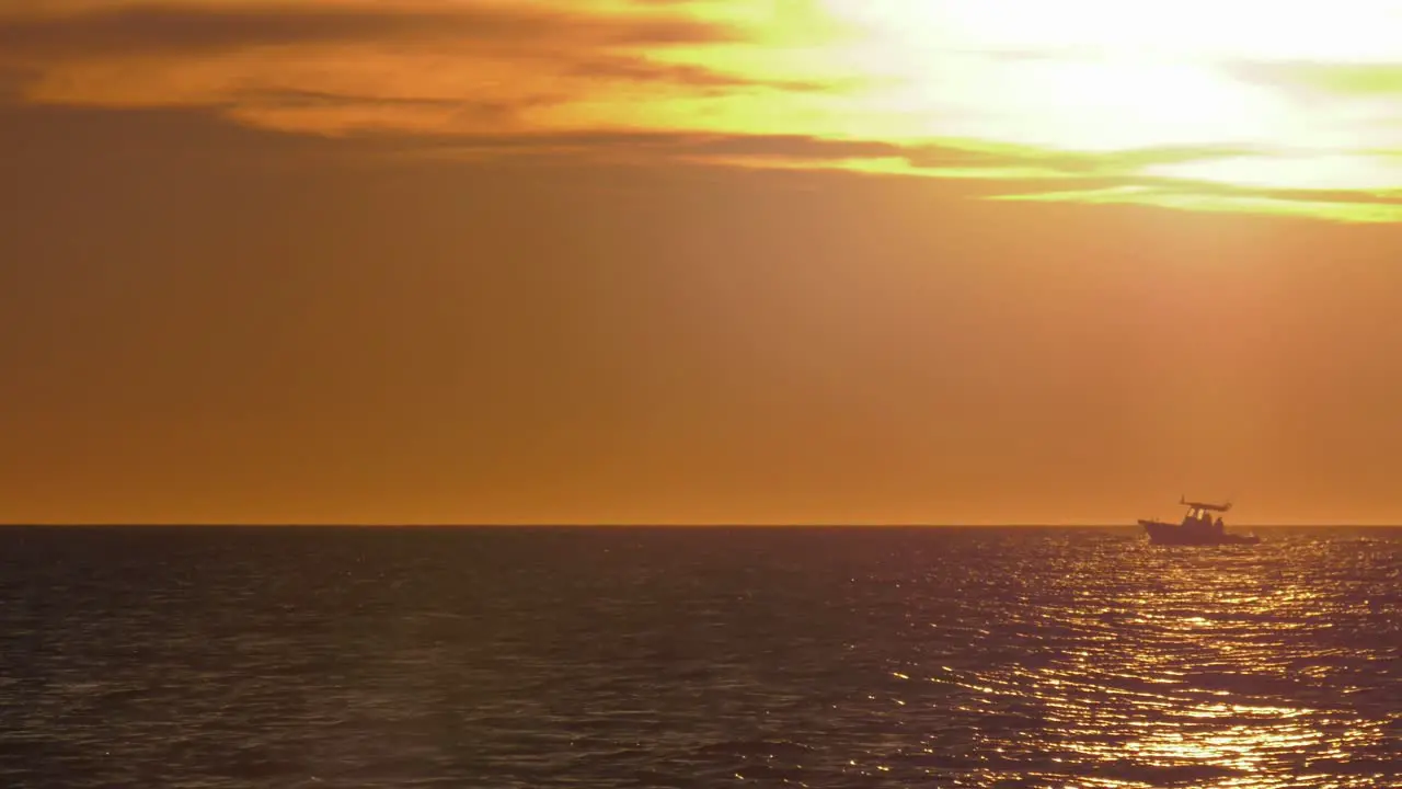 Motorboat on horizon with golden sunlight on water mediterranean coast spain