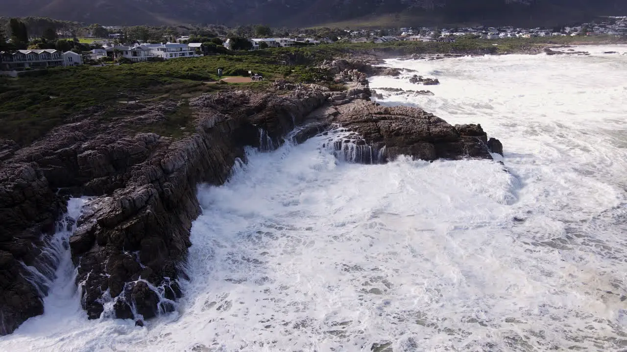 Frothing seawater and crashing waves along rocky coastline of Hermanus aerial