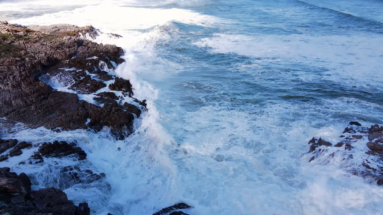 Whitewash created on shoreline as ocean waves surges against jagged rocks