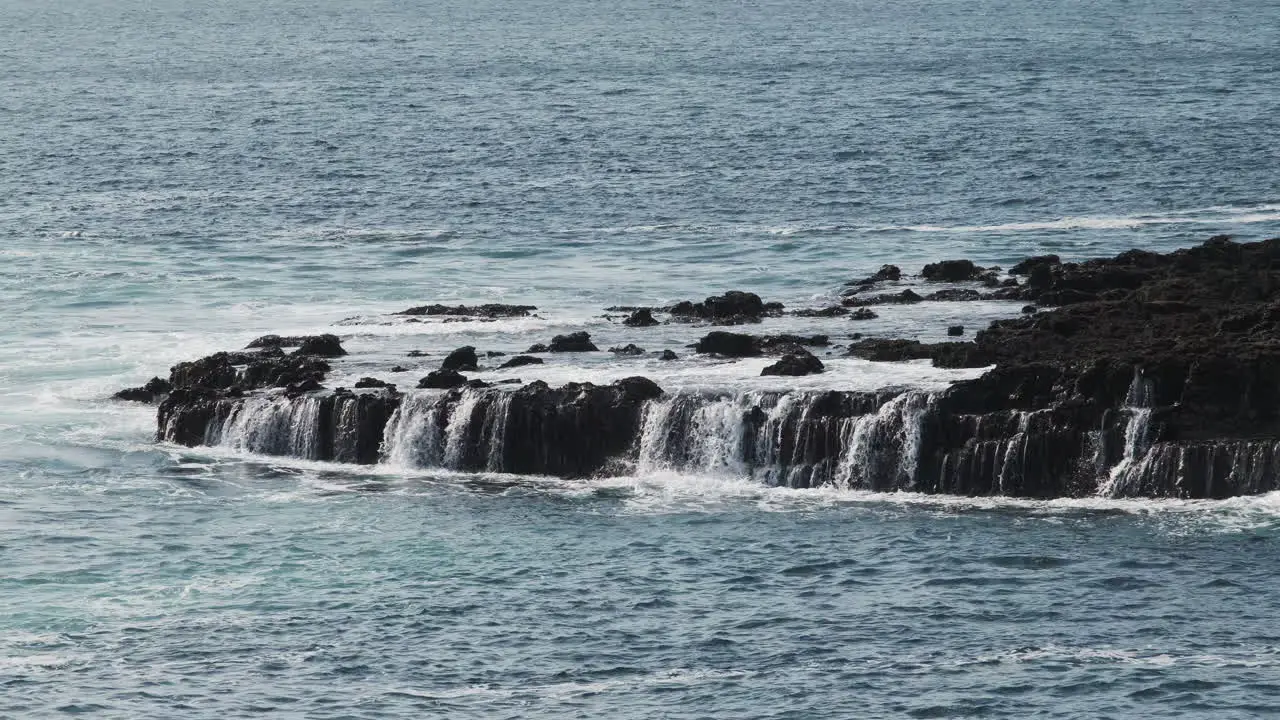 Water draining from ocean waves on rocky shoreline