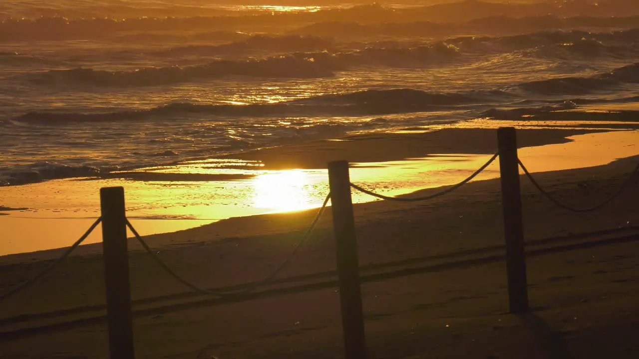 Sandy beach with waves breaking onto shore reflecting sunrise mediterranean sea coastal view spain