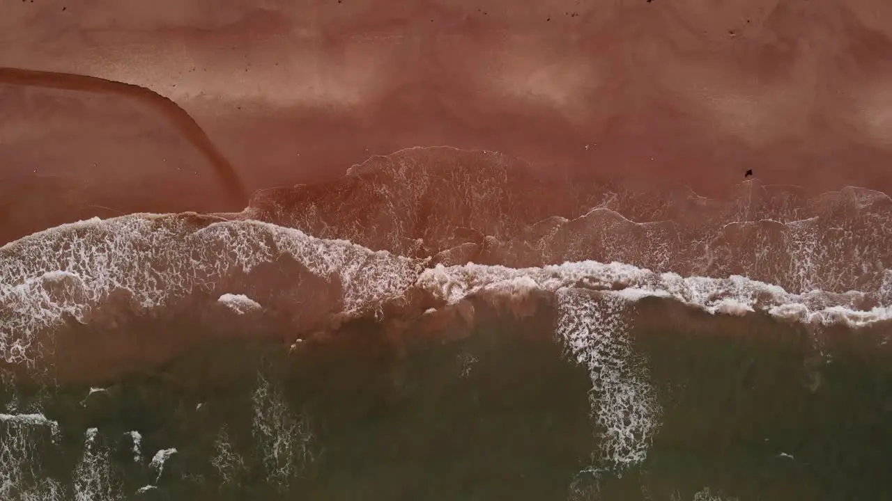 4k Aerial of empty sand beach with wide waves while slowly moving closer to the shoreline