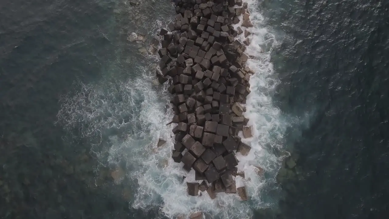 waves crashing over a spit of rocks in the sea