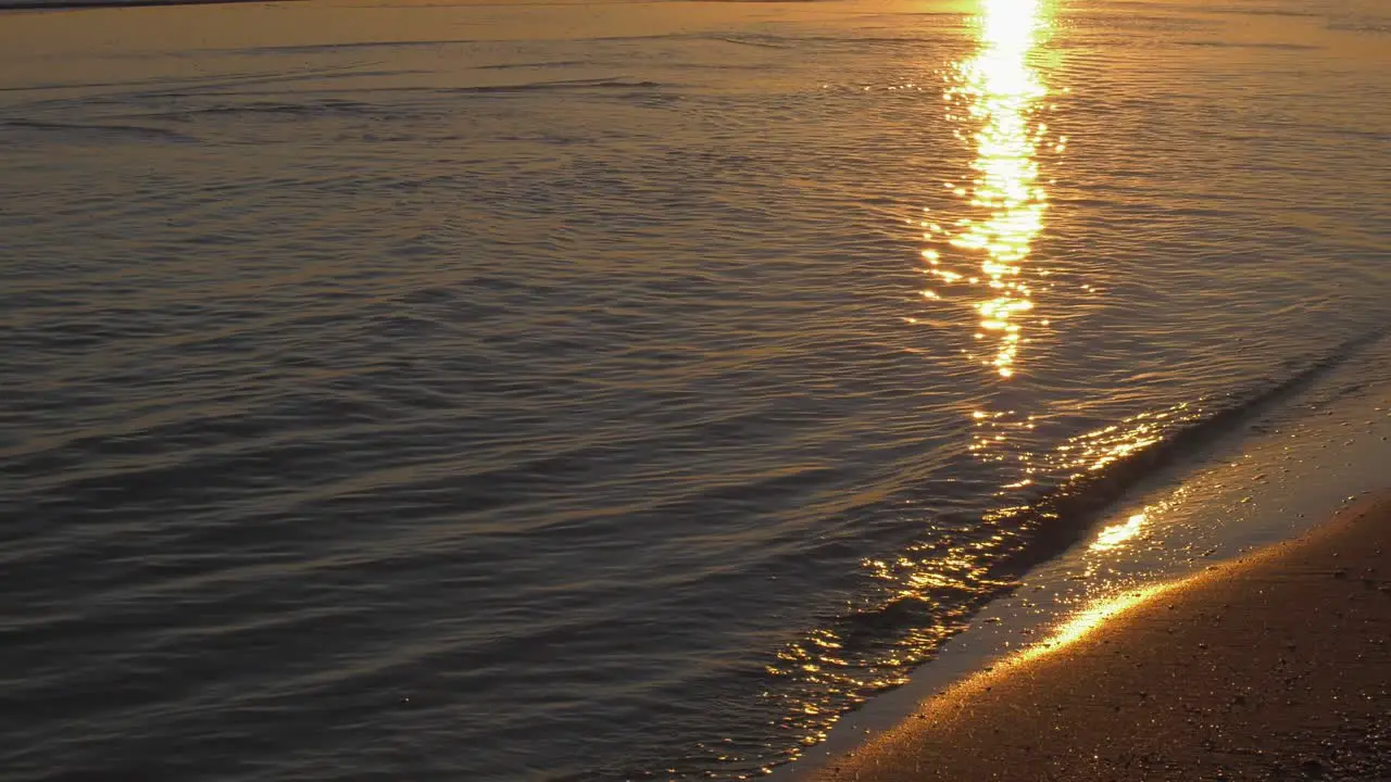 Calm Shallow waves on sandy shore reflecting sunrise mediterranean coastal seascape