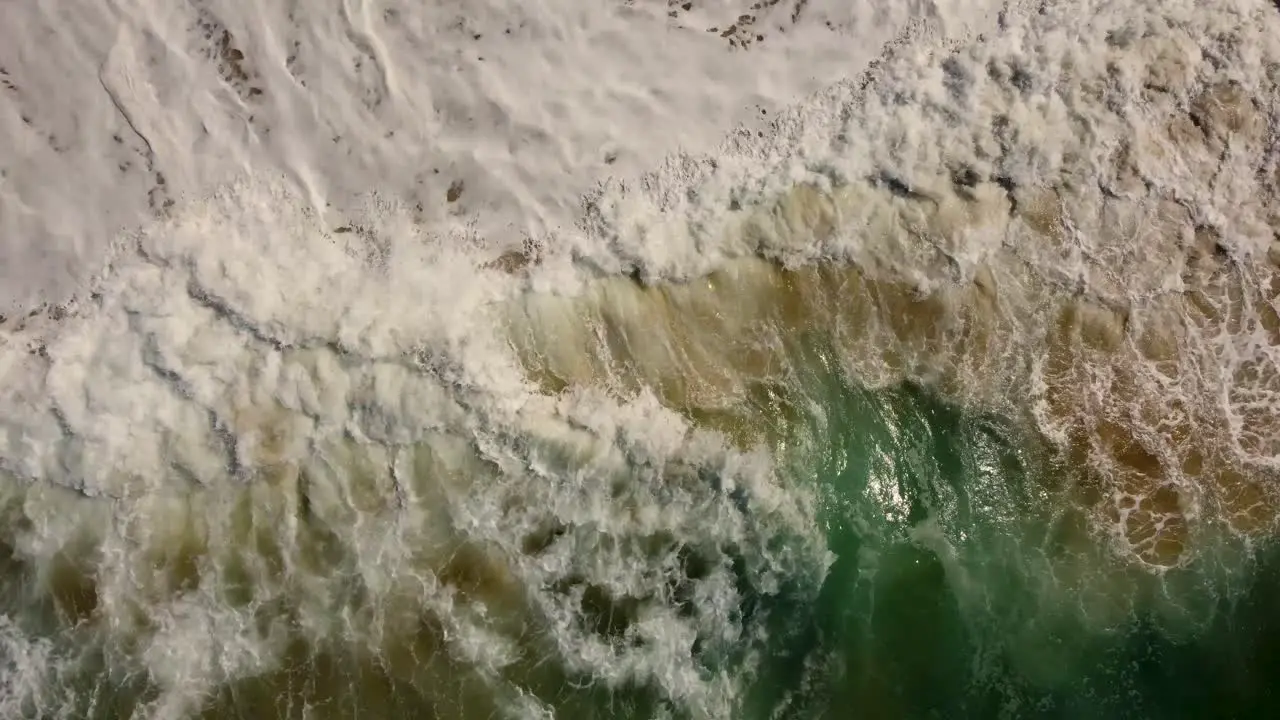 Drone aerial shot of ocean water splashing onto sand close-up Central Coast beach NSW Australia 4K