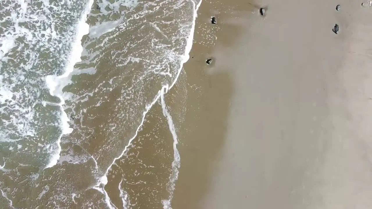 Top down aerial view of waves crashing on a beach