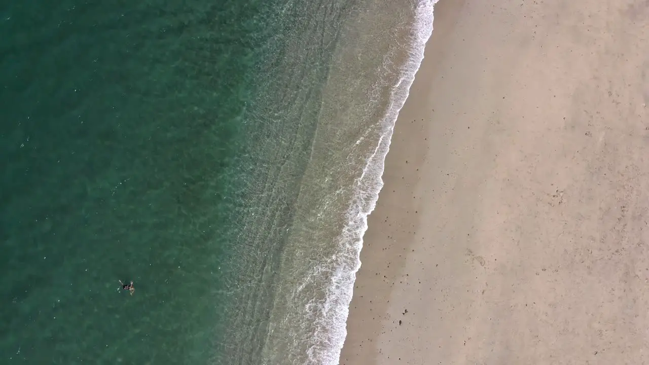 Waves Crashing on Beach with People Swimming and Standing Aerial View