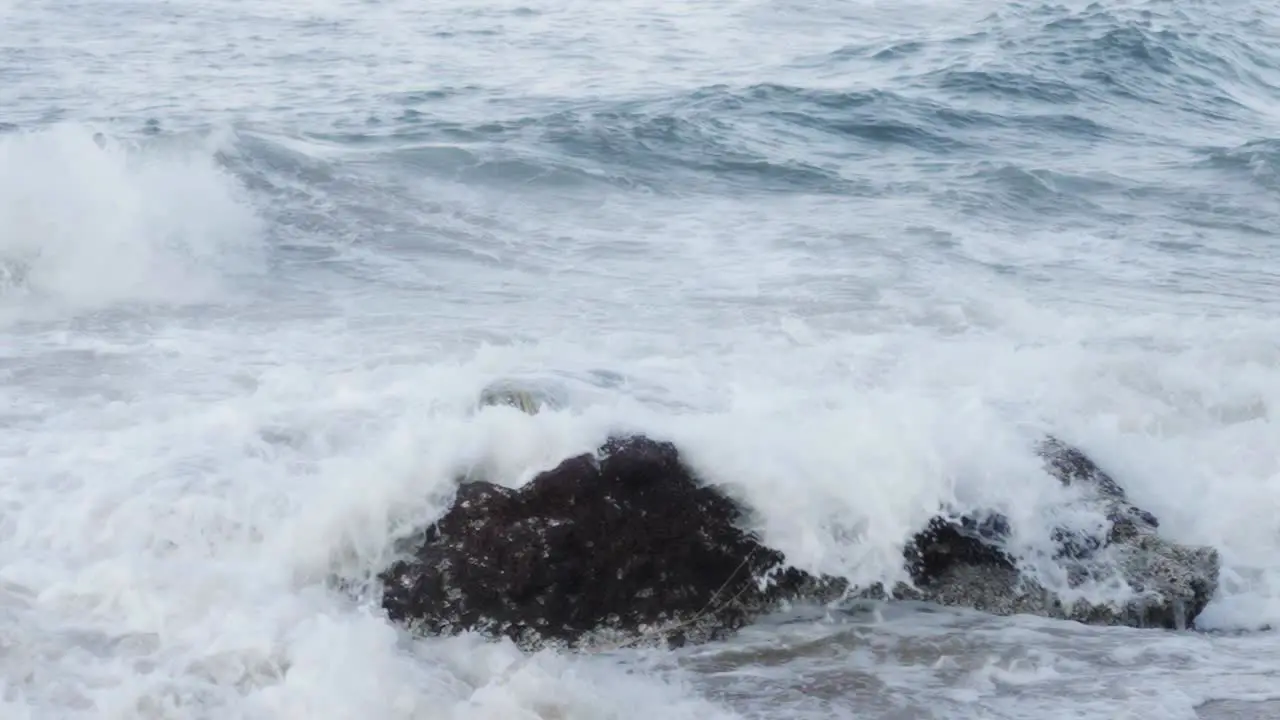 Slow motion of sea waves breaking on the shore with sea foam