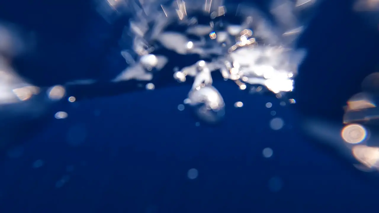 Jumping into deep blue ocean water and swimming through choppy swell waves and bubbles in vast remote sea