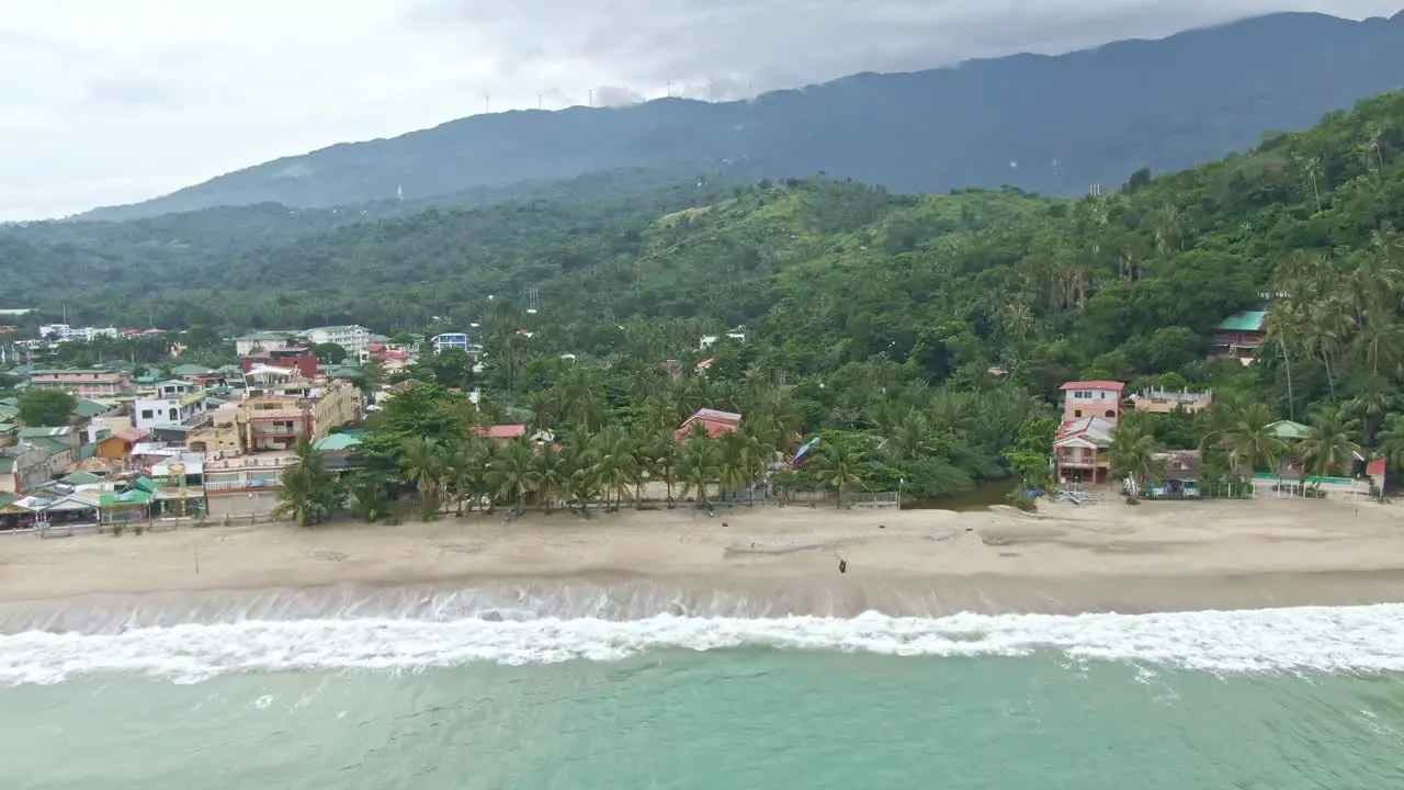 Nice beach view of waves crashing through the sandy seashore silhouetted mountains with a cloudy sky above