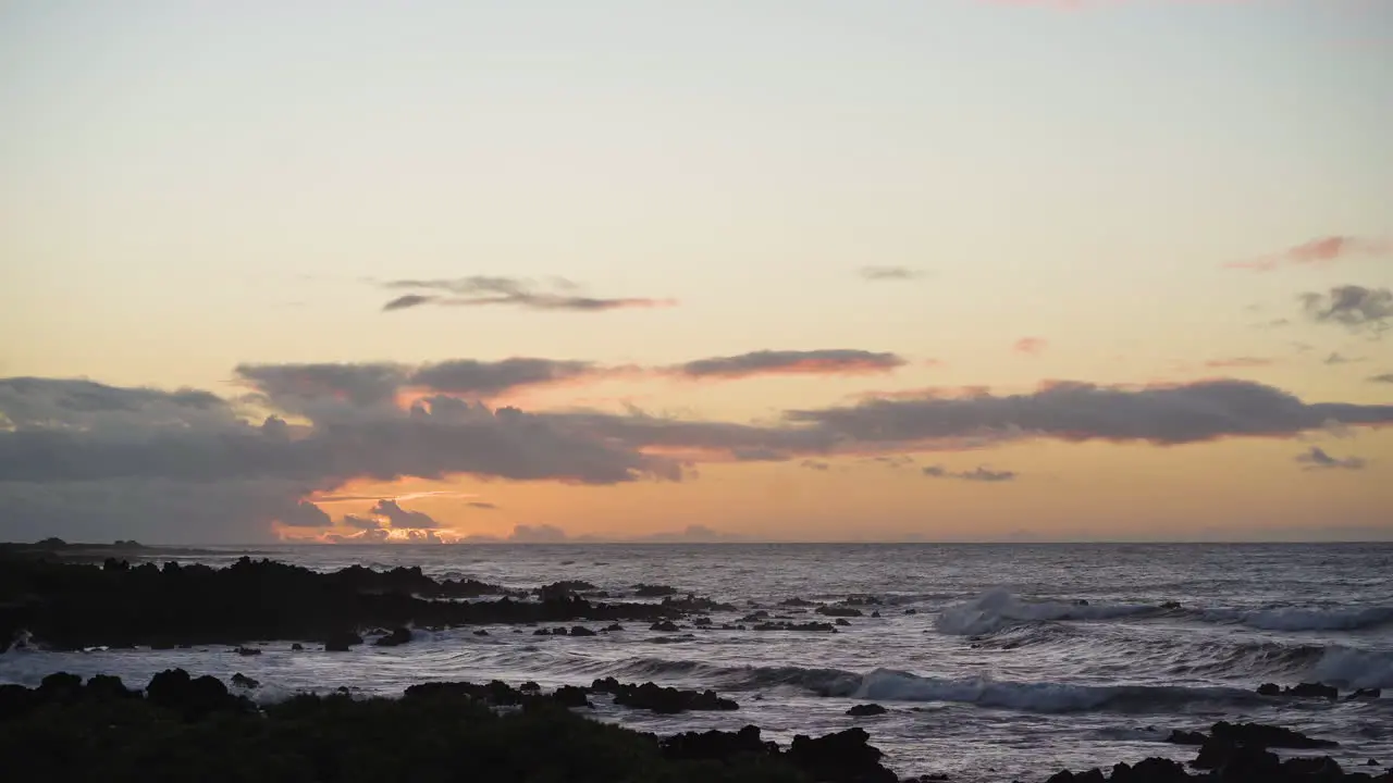 Calm serene sunset with waves rushing toward rocky beach at sunset