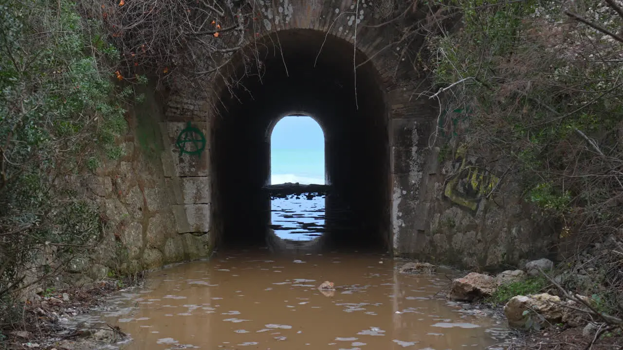 A tunnel leads towards a wild sea where incoming waves create a rippling effect