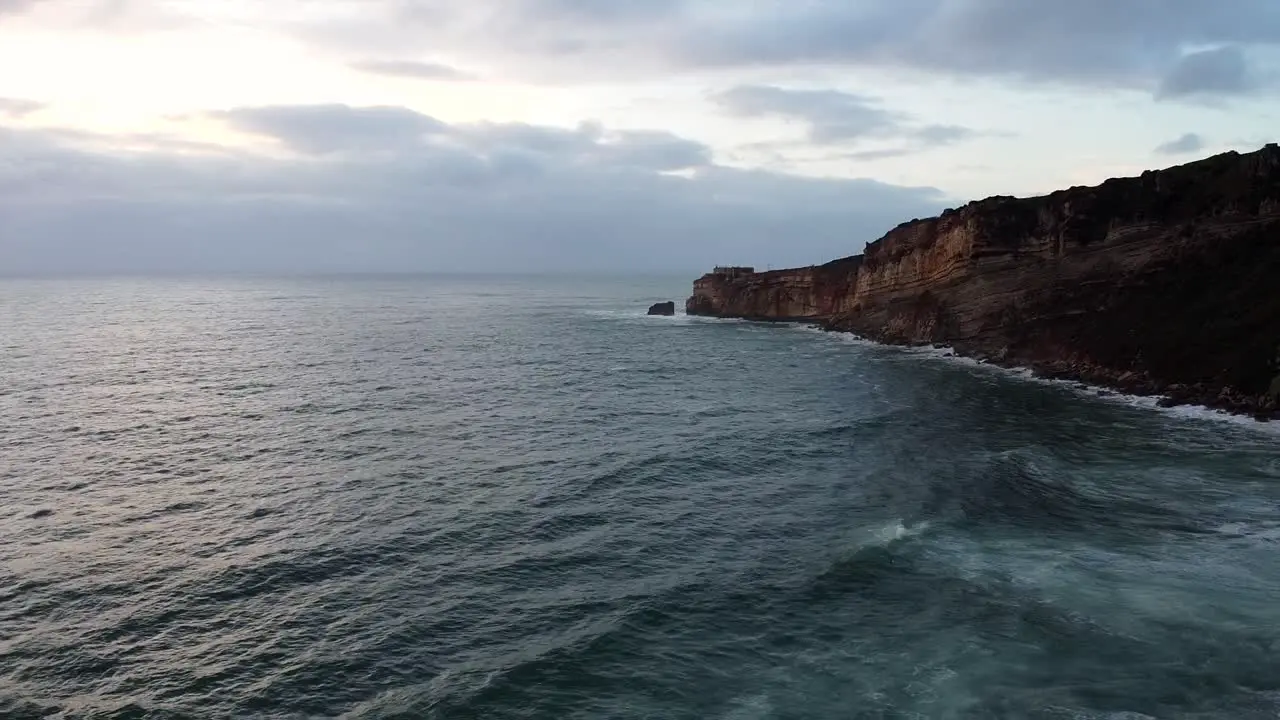 Aerial View Of Calm Atlantic Ocean Waves Beside Nazare Coastline Cliffs