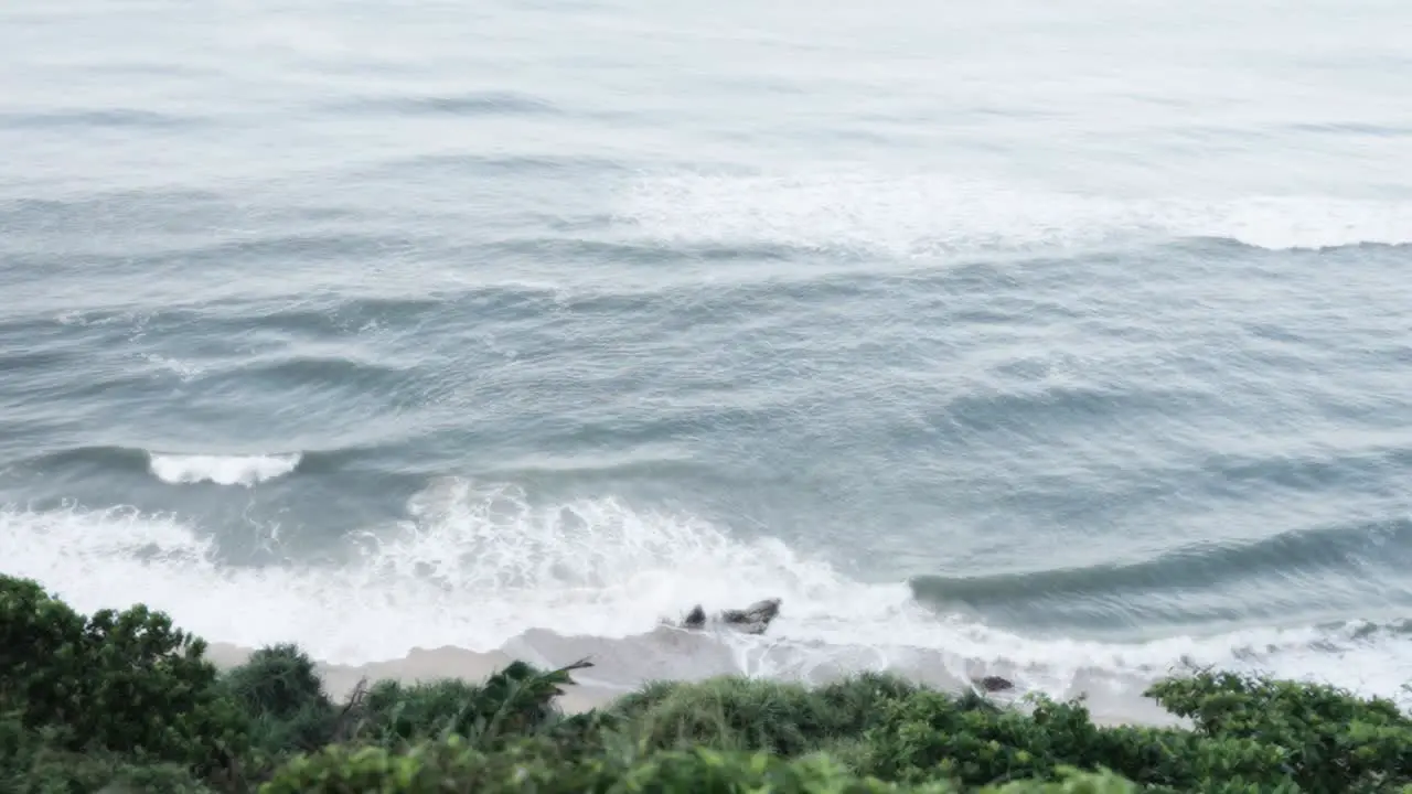 Aerial view of sea waves crashing against a cliff rock