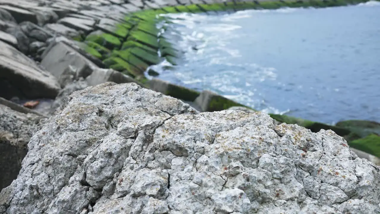 Close up of rock with sea and wave breakers in background