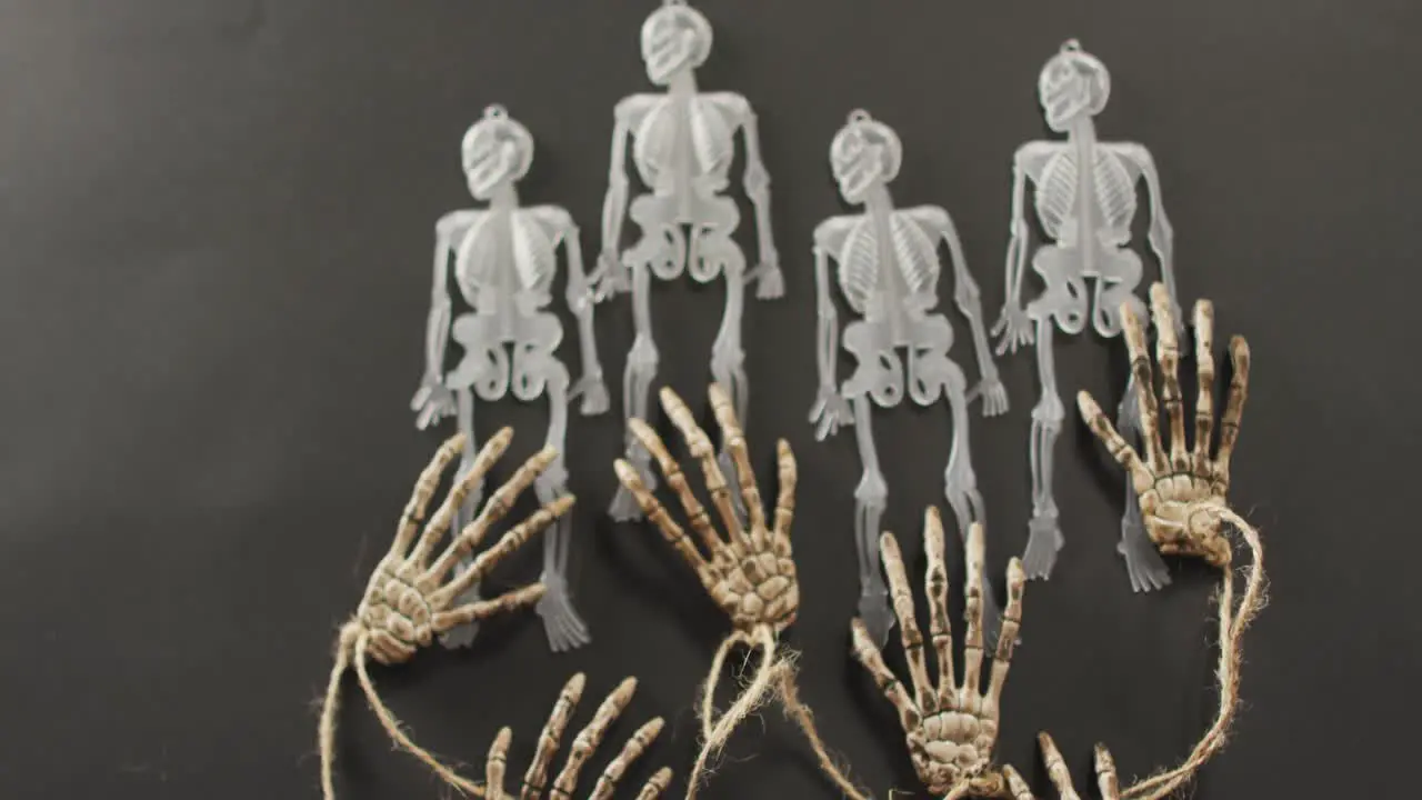 Multiple skeleton toys and skeleton hands with copy space on grey background