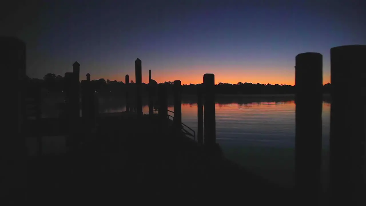 Tracking shot of a river dock in silhouette at sunrise