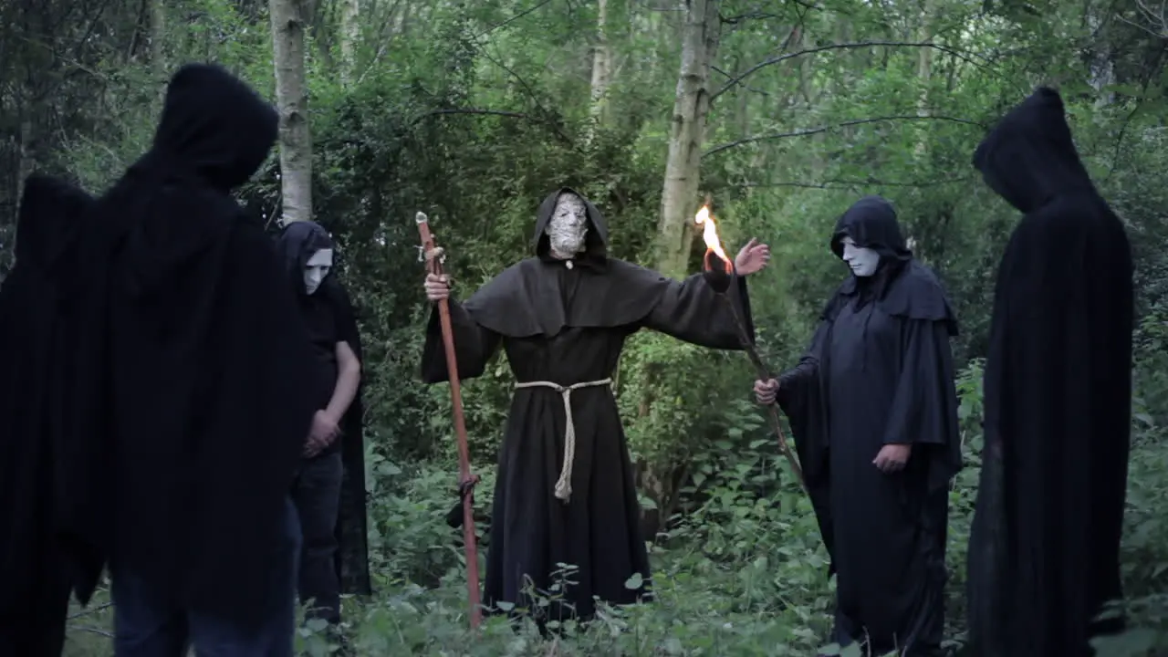 A circle of evil hooded druids in a cult performing a sorcery ritual