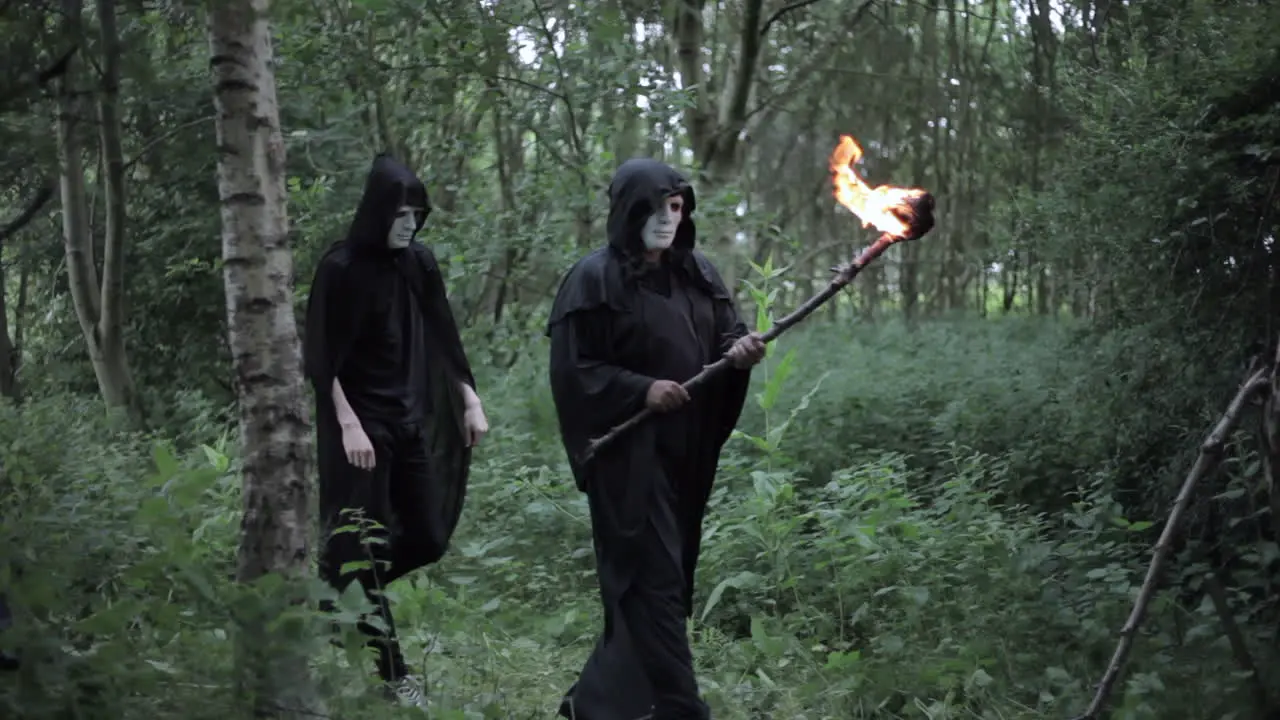 A cult of evil hooded druids are walking in the woods and about to perform a sacrifice ritual