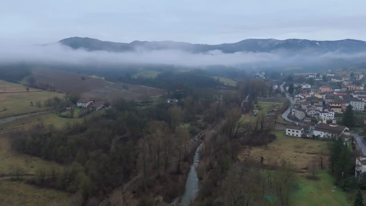 Mist cloud over countryside river valley with village and overcast sky