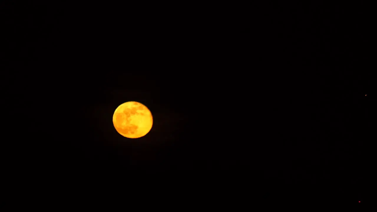 large orange full moon moving in real-time against a pure black background