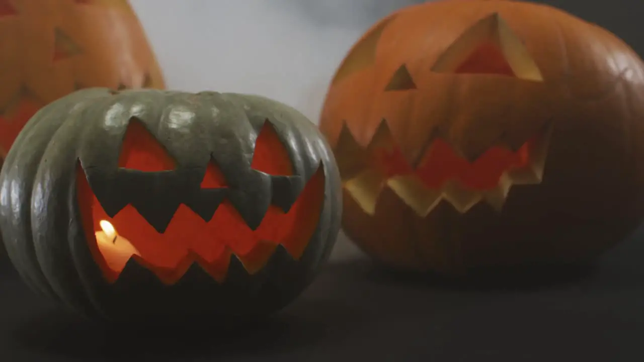 Smoke effect over multiple scary face carved halloween pumpkin against grey background