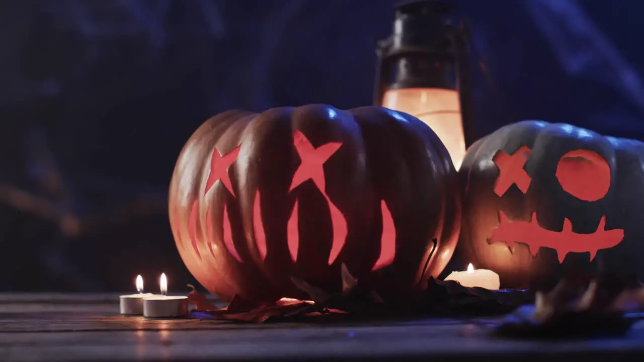 Video of halloween carved pumpkins candles and smoke with copy space on blue background