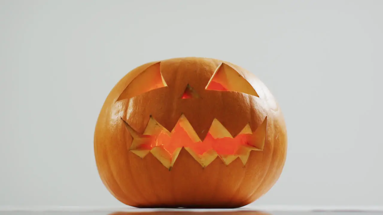 Close up view of scary face carved halloween pumpkin against grey background