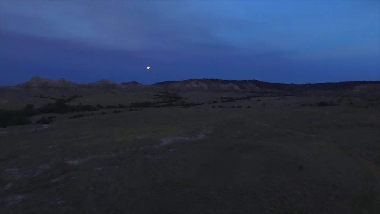 A slow cinematic drone shot panning towards the moon at dusk