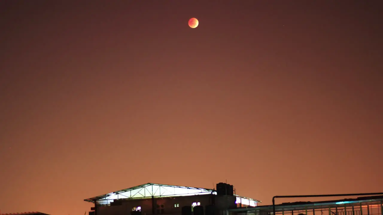 Blood moon rising and transition time lapse with a building in the foreground and red sky in the background