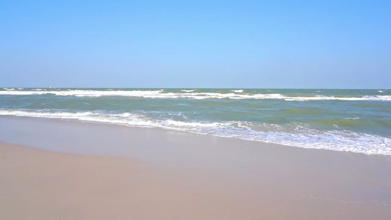 Waves slowly wash up on a golden tropical beach