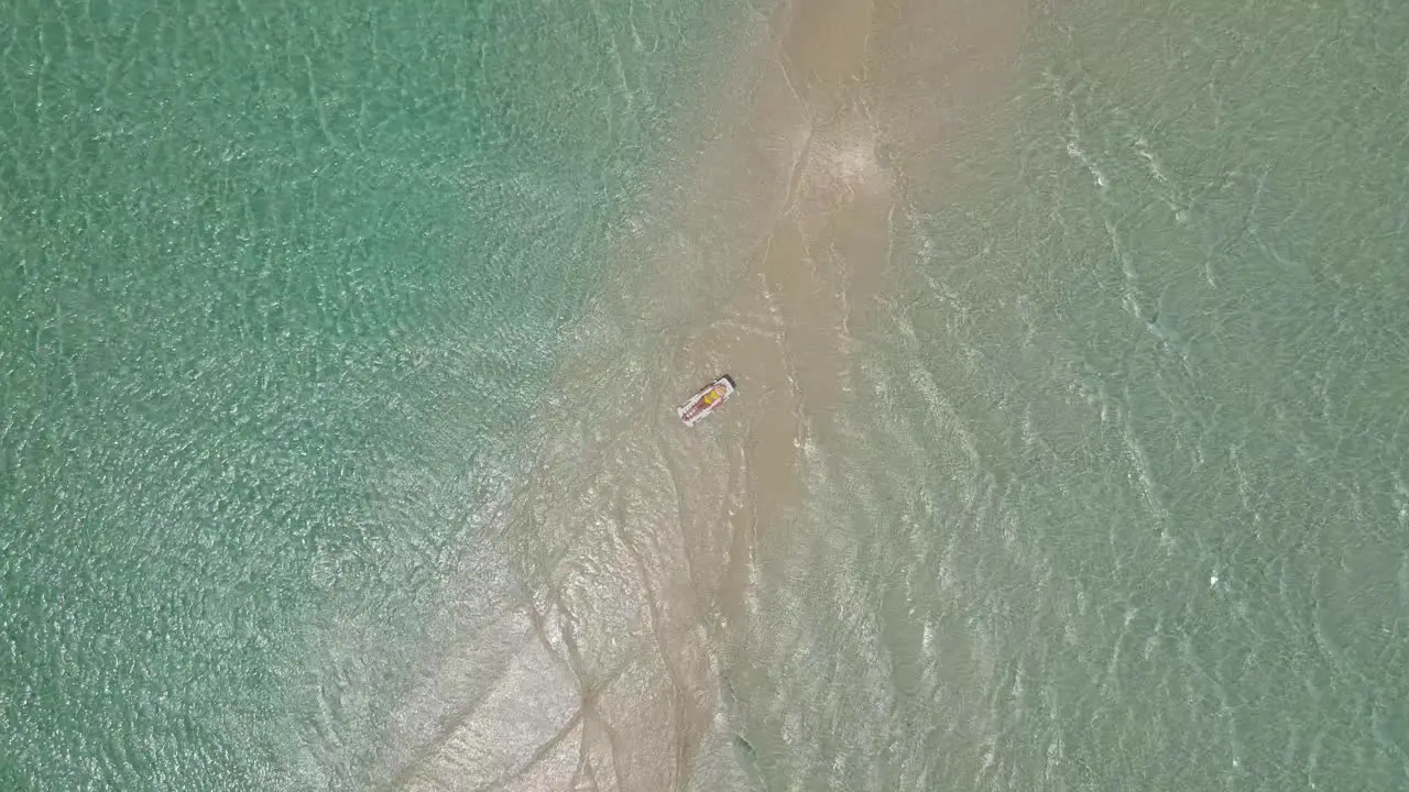 Young girl in yellow swimsuit lying on a sunbed on a sandbank in shallow turquoise waters of indian ocean in maldives